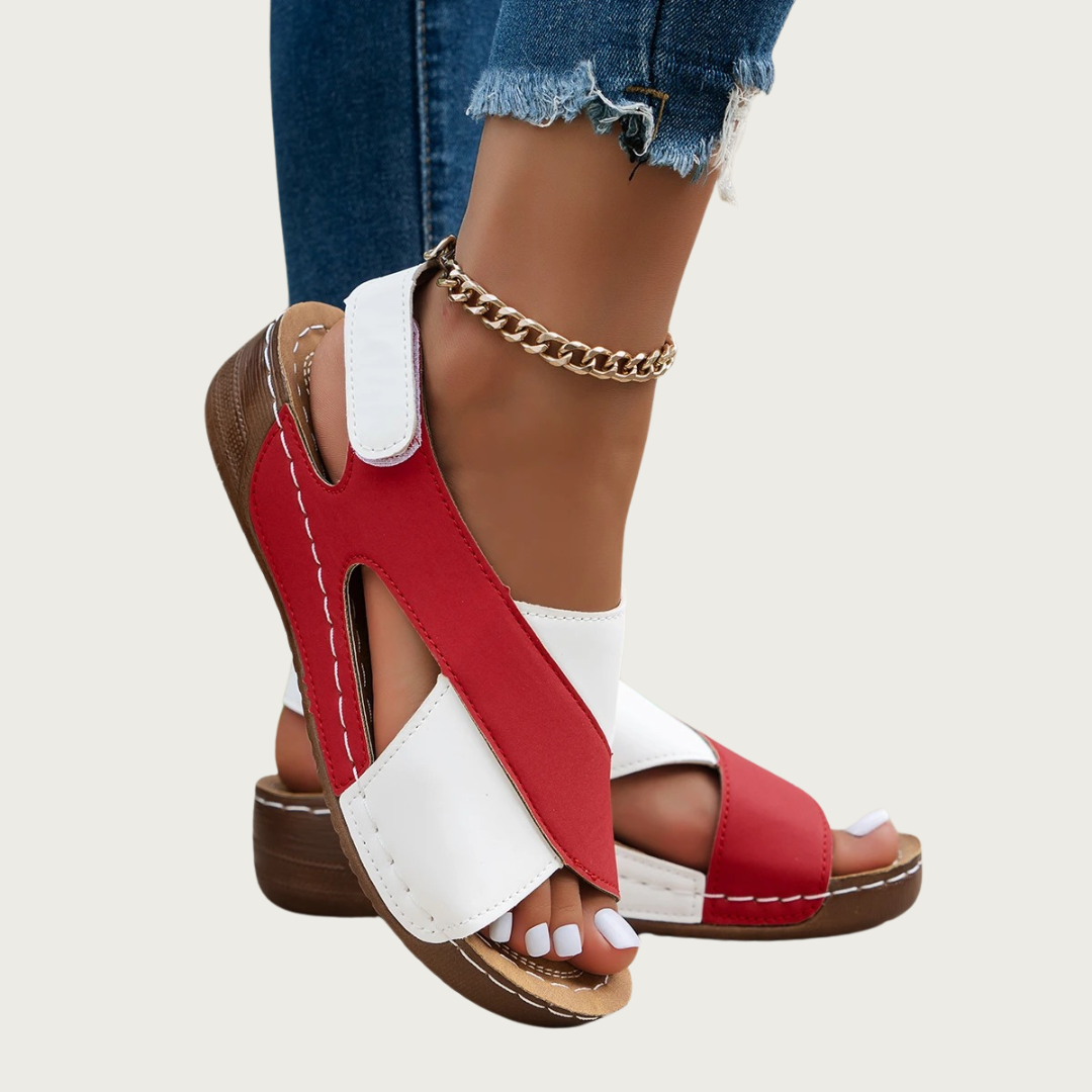 Sandales rouges et blanches pour femme, talon compensé, lanières croisées, portées avec un jean déchiré et bracelet chaîne doré. Mode estivale tendance.