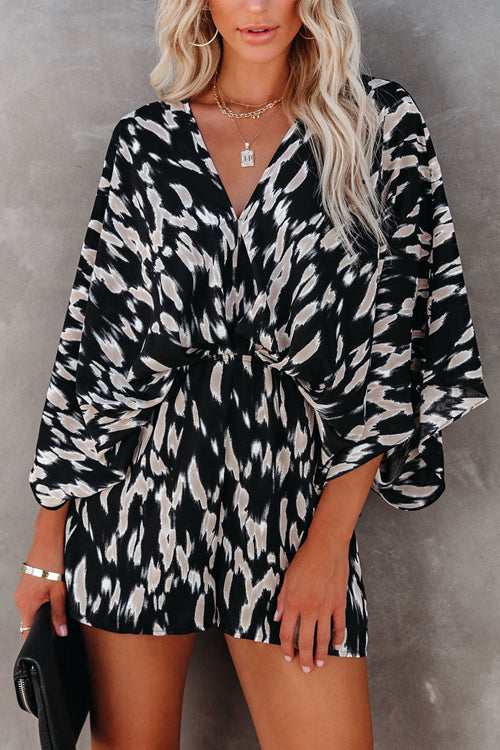 Robe courte à motifs noirs et blancs, manches chauve-souris, portée par une femme blonde. Style chic et moderne, idéal pour une soirée élégante.