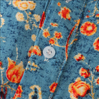 Chemise en tissu bleu à motif floral orange et jaune, bouton blanc en plastique. Mode tendance, style vintage, vêtements imprimés floraux.
