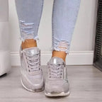 Jeans déchirés et baskets argentées brillantes pour femme sur sol en bois, mode tendance, style décontracté, chaussures élégantes et confortables.
