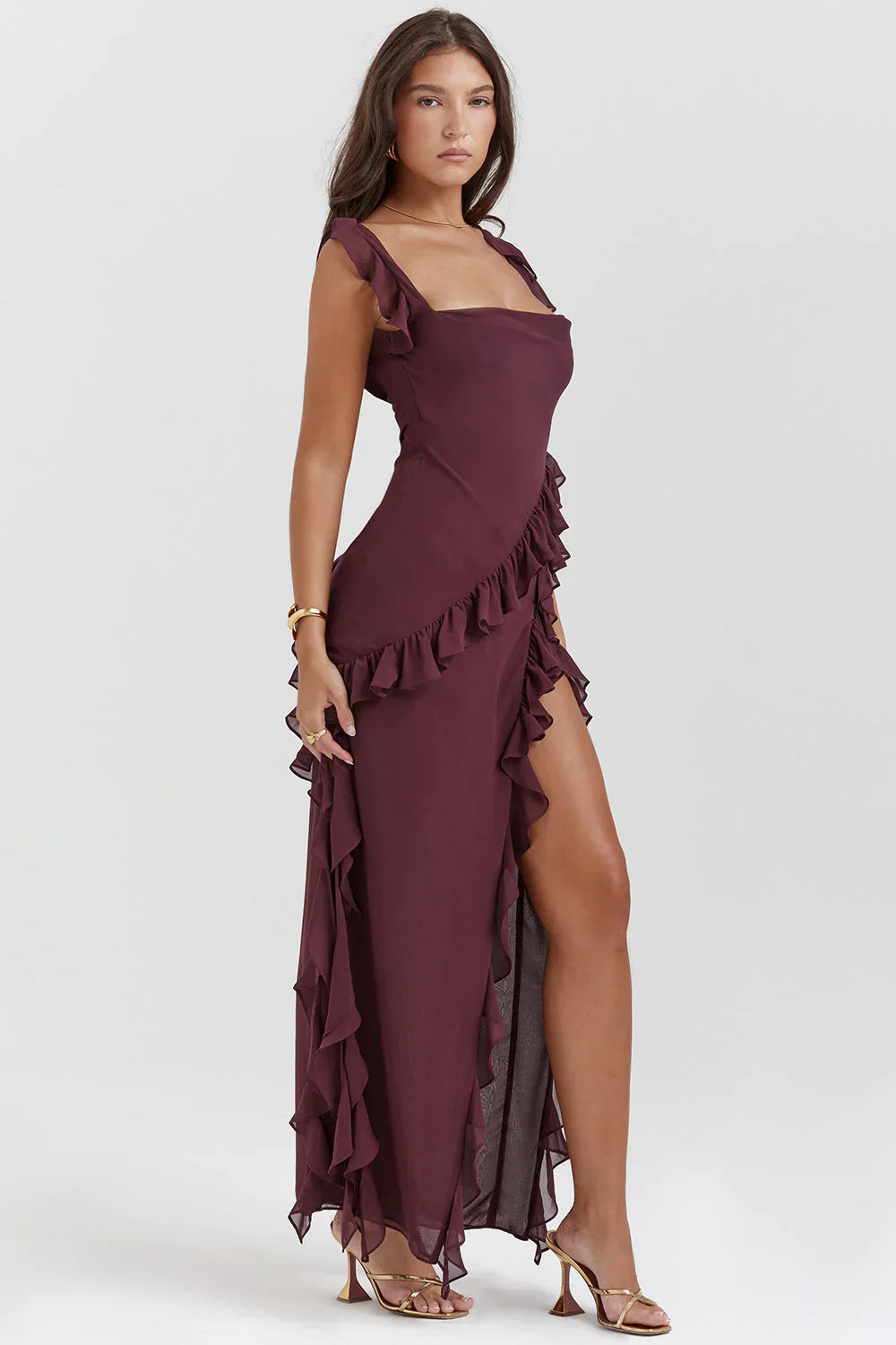 Robe longue bordeaux élégante avec volants, fente haute, portée par une femme. Mode féminine chic, tendance soirée, style glamour.