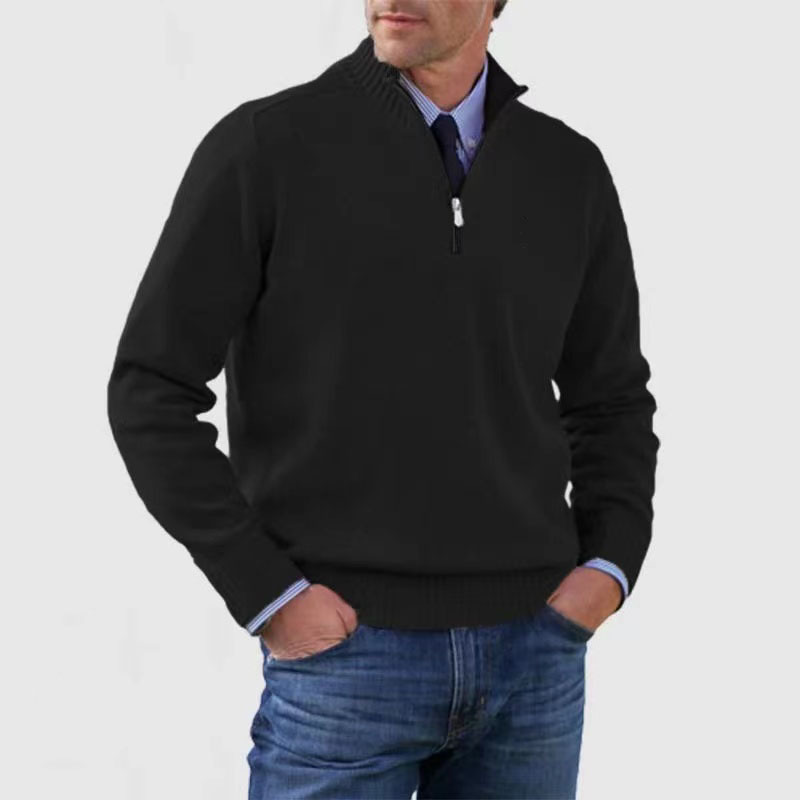 Homme portant un pull noir à col zippé, manches longues, sur une chemise bleue, avec un jean bleu. Mode masculine élégante et décontractée.