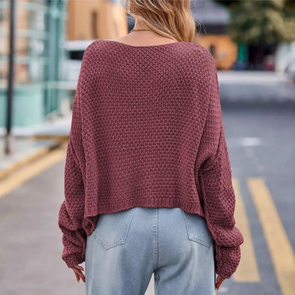 Femme portant un pull en tricot rose ample et un jean bleu clair, marchant en ville. Mode automne, style décontracté, tendance urbaine.