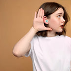 Jeune femme écoutant attentivement, main derrière l'oreille, sur fond beige. Concept d'écoute active et de communication.