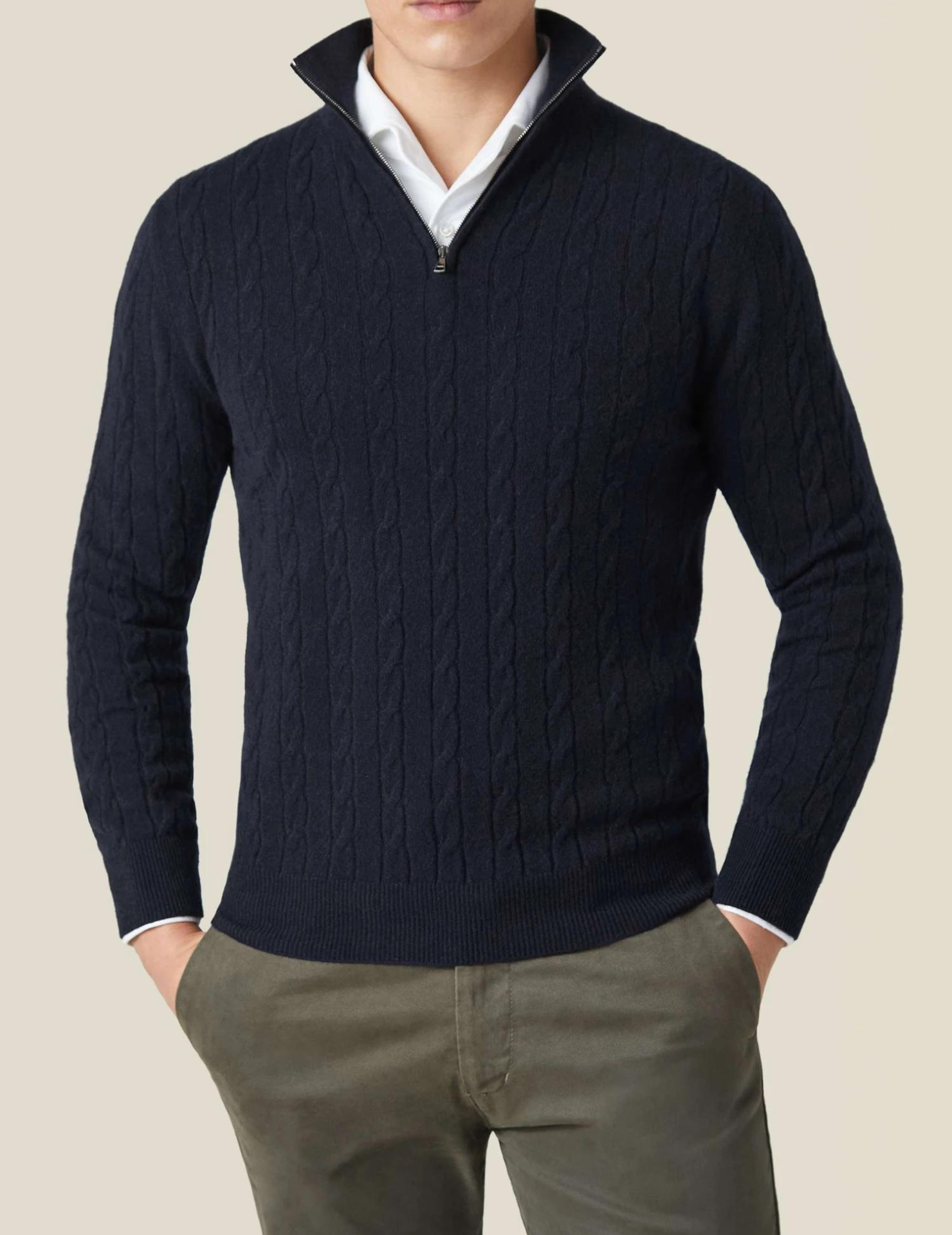 Homme portant un pull bleu marine à col zippé, motif torsadé, sur chemise blanche, avec pantalon kaki. Mode masculine élégante et décontractée.