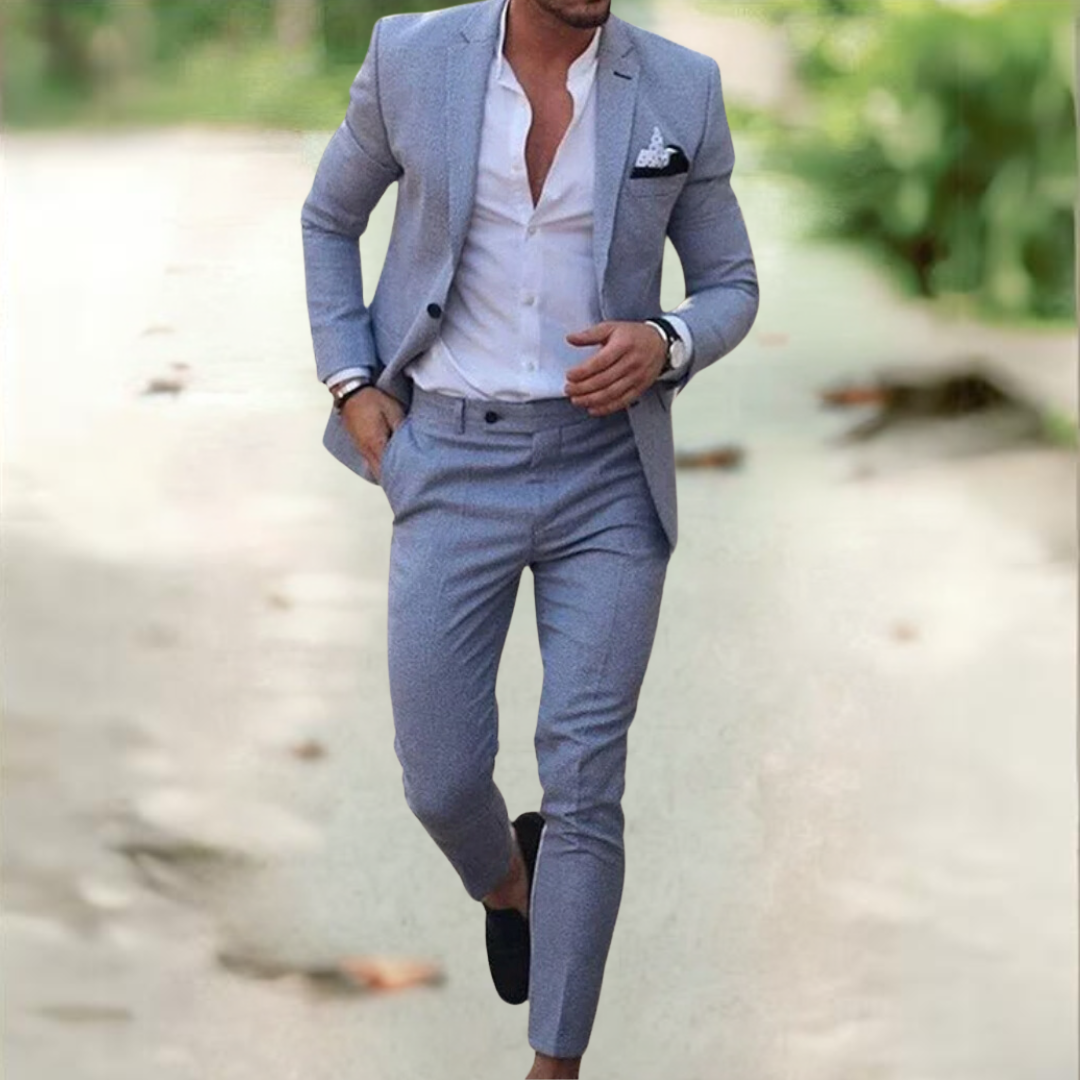 Homme en costume gris élégant, chemise blanche ouverte, marchant en extérieur. Mode masculine, style chic, tenue décontractée.