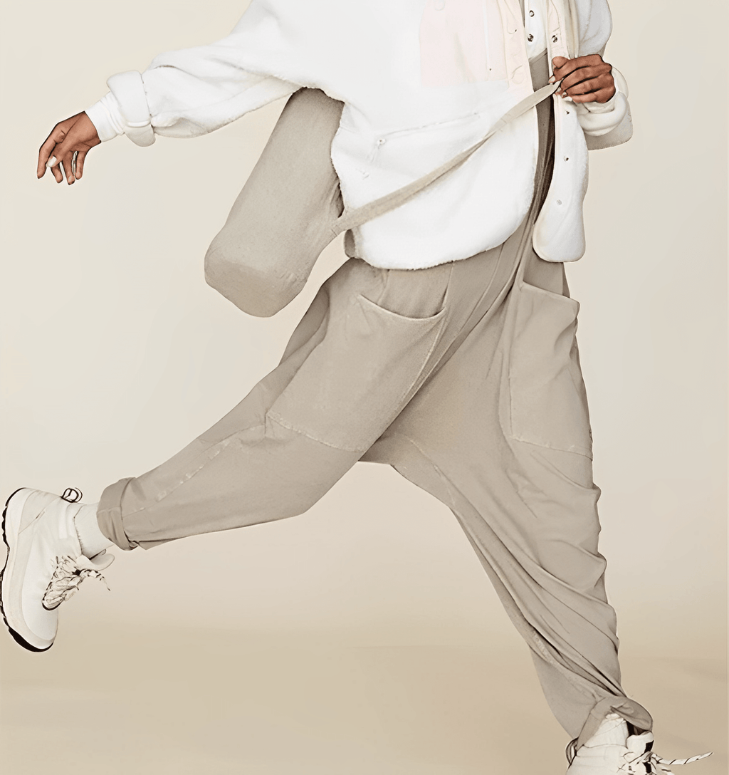 Personne portant un sweat blanc et un pantalon ample beige, sautant avec des baskets blanches. Mode décontractée, style urbain, tendance streetwear.