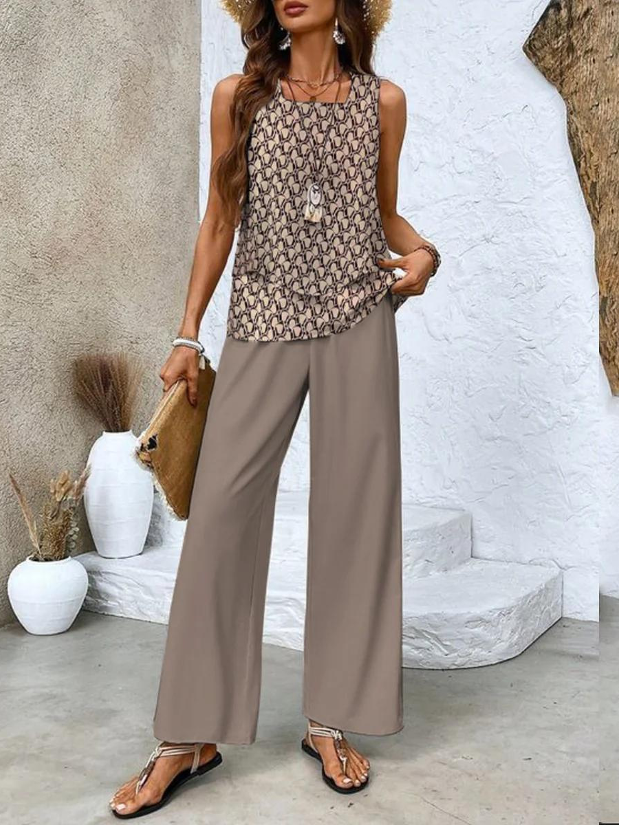 Femme en tenue estivale chic, portant un débardeur imprimé et un pantalon ample beige, accessoirisée de sandales et d'un chapeau de paille.