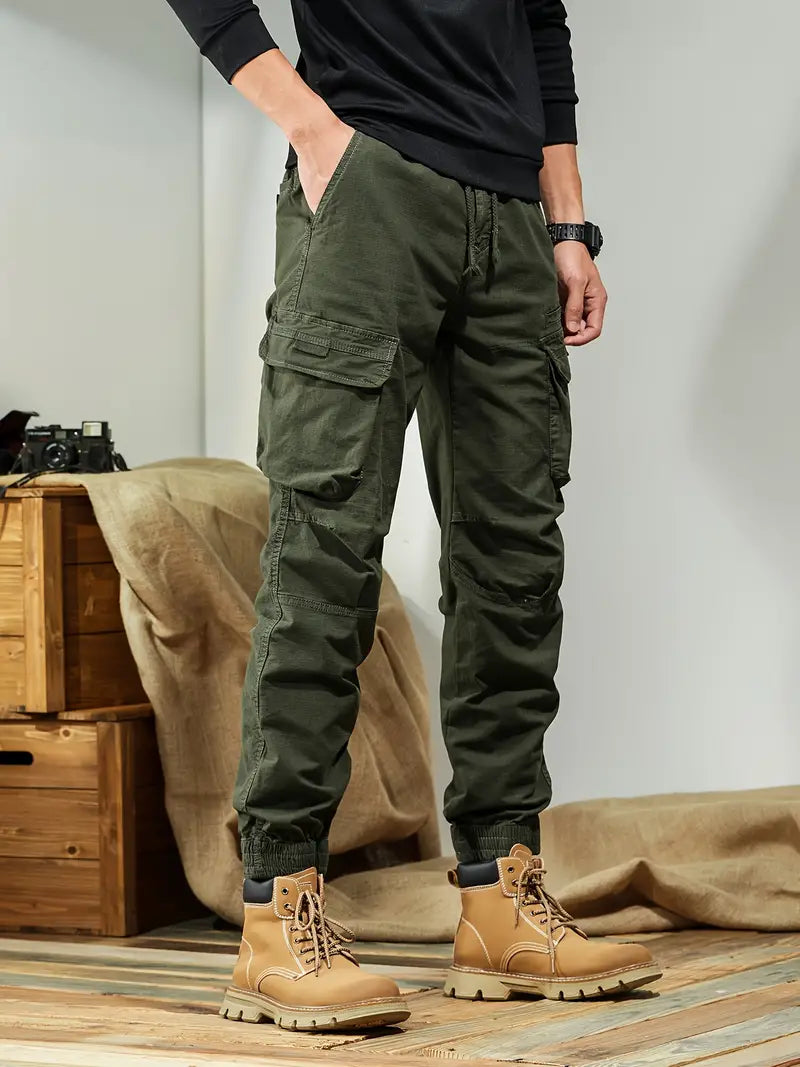 Pantalon cargo vert pour homme avec poches multiples, associé à des bottes marron robustes. Style décontracté et fonctionnel pour mode masculine.