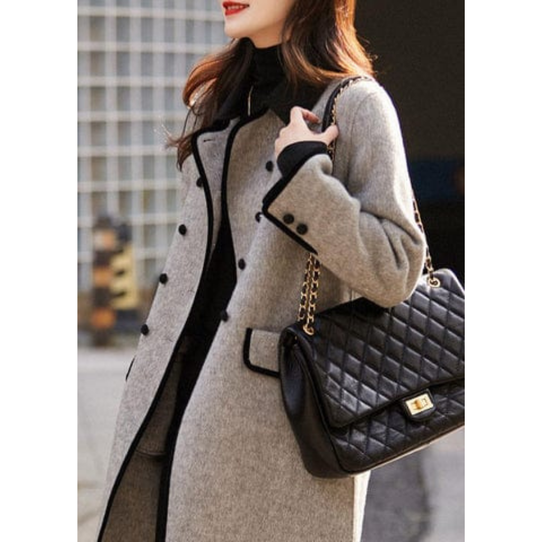 Femme portant un manteau gris élégant avec sac à main noir matelassé à chaîne dorée, mode automne chic, style urbain sophistiqué.