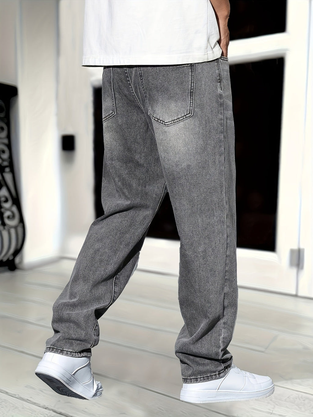 Jeans baggy gris pour homme, style décontracté, avec coutures apparentes, portés avec des baskets blanches, mode urbaine tendance.