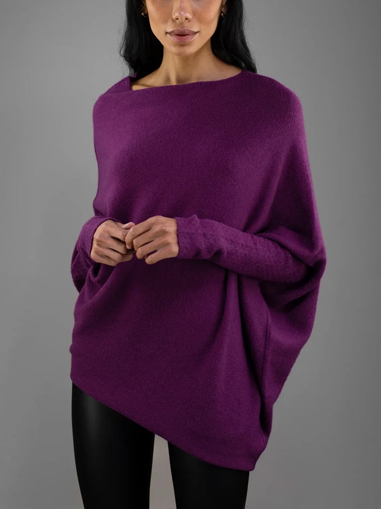 Femme portant un pull ample violet, manches longues, col bateau, sur fond gris. Mode automne-hiver, style décontracté et élégant.