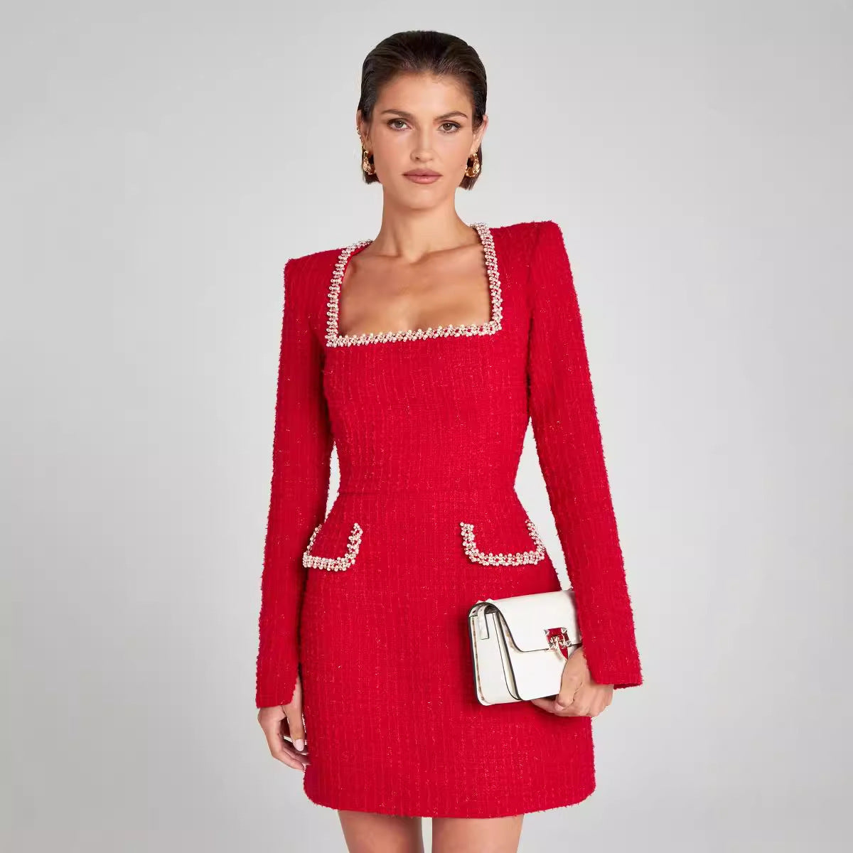 Robe rouge élégante avec détails perlés, manches longues, col carré, portée par une femme. Mode féminine chic, tendance automne-hiver.