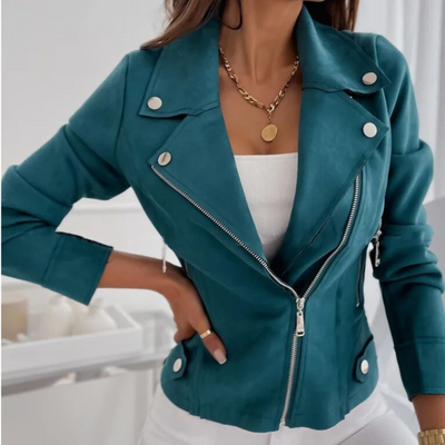 Femme portant une veste en cuir bleu-vert avec fermeture éclair argentée, boutons blancs, collier doré, et top blanc. Mode élégante et tendance.