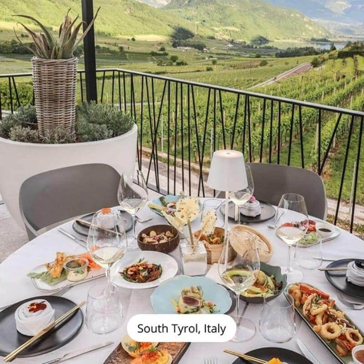 Table élégante avec plats gastronomiques et verres de vin, vue panoramique sur vignobles du Tyrol du Sud, Italie. Repas en terrasse, paysage pittoresque.