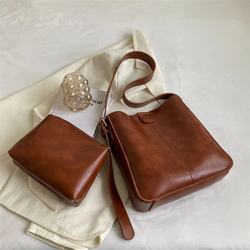 Sac à main en cuir marron avec pochette assortie sur fond blanc, accessoire mode élégant, design minimaliste, idéal pour tenues décontractées.