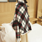 Cape à carreaux noirs, blancs et rouges sur un lit dans une chambre moderne en bois. Accessoire de mode élégant et tendance pour l'hiver.