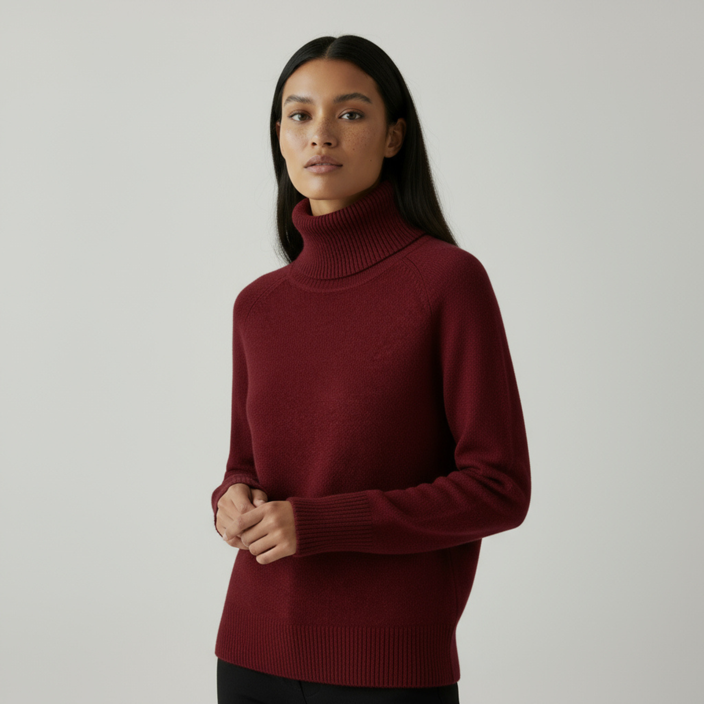 Femme portant un pull col roulé bordeaux, manches longues, sur fond neutre. Mode automne-hiver, style élégant et confortable.