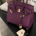 Sac à main en cuir violet avec fermetures dorées, posé sur une table noire, accompagné de maquillage Chanel. Accessoire de luxe élégant.