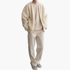 Homme portant un ensemble beige élégant avec un pull, un pantalon ample et des baskets à carreaux. Mode masculine décontractée et tendance.