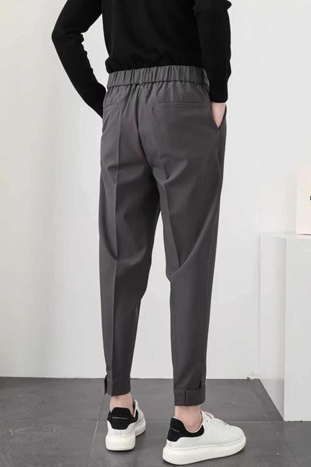Pantalon gris homme, coupe décontractée, taille élastique, poches latérales, porté avec des baskets blanches et noires, style moderne et confortable.