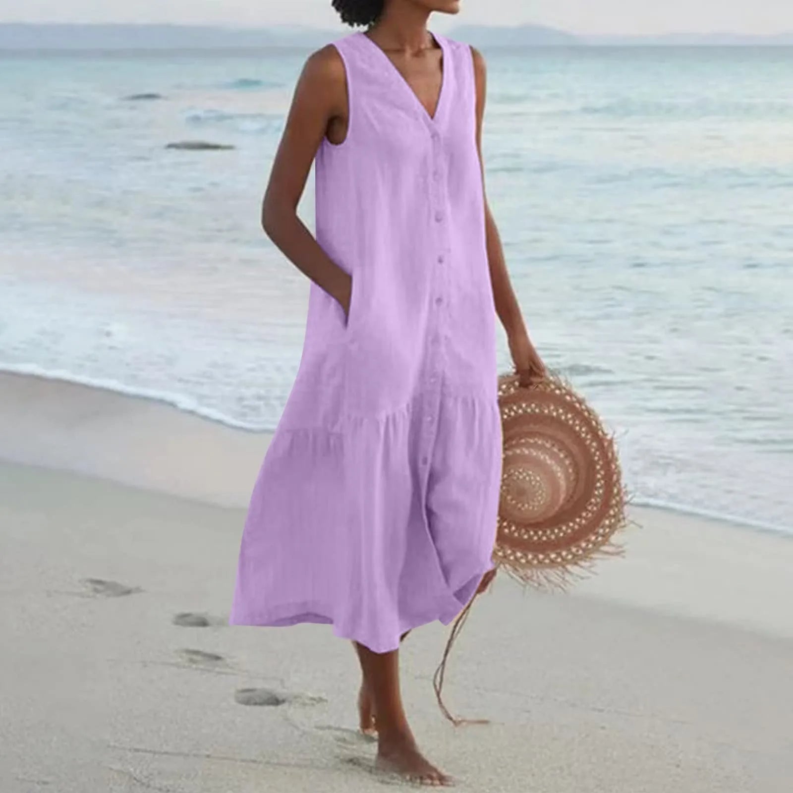 Robe d'été violette sans manches, femme marchant sur la plage avec un chapeau de paille rond, mer en arrière-plan. Mode plage élégante.