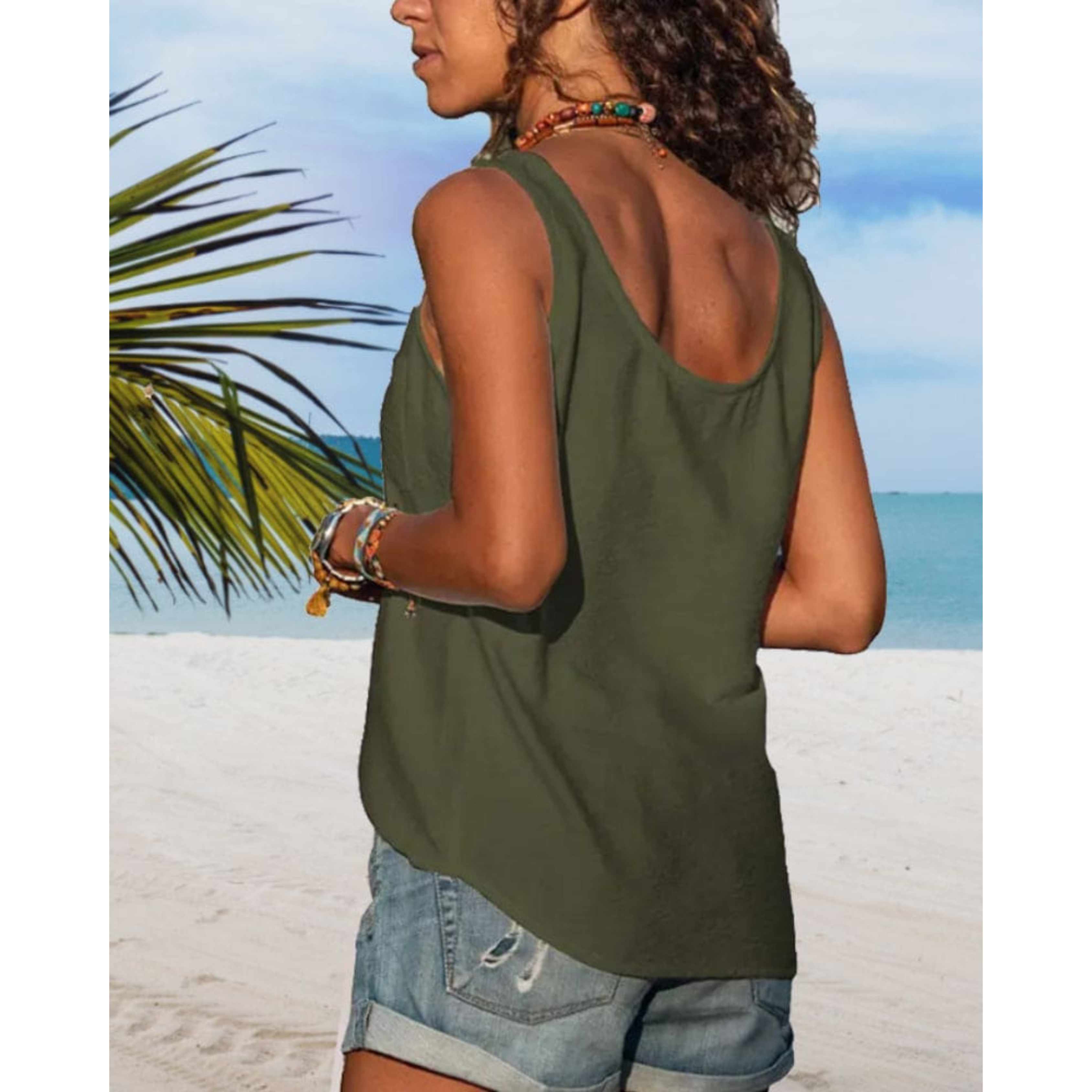 Femme en débardeur vert et short en jean sur plage tropicale, mer turquoise en arrière-plan, bracelets colorés, ambiance estivale et décontractée.