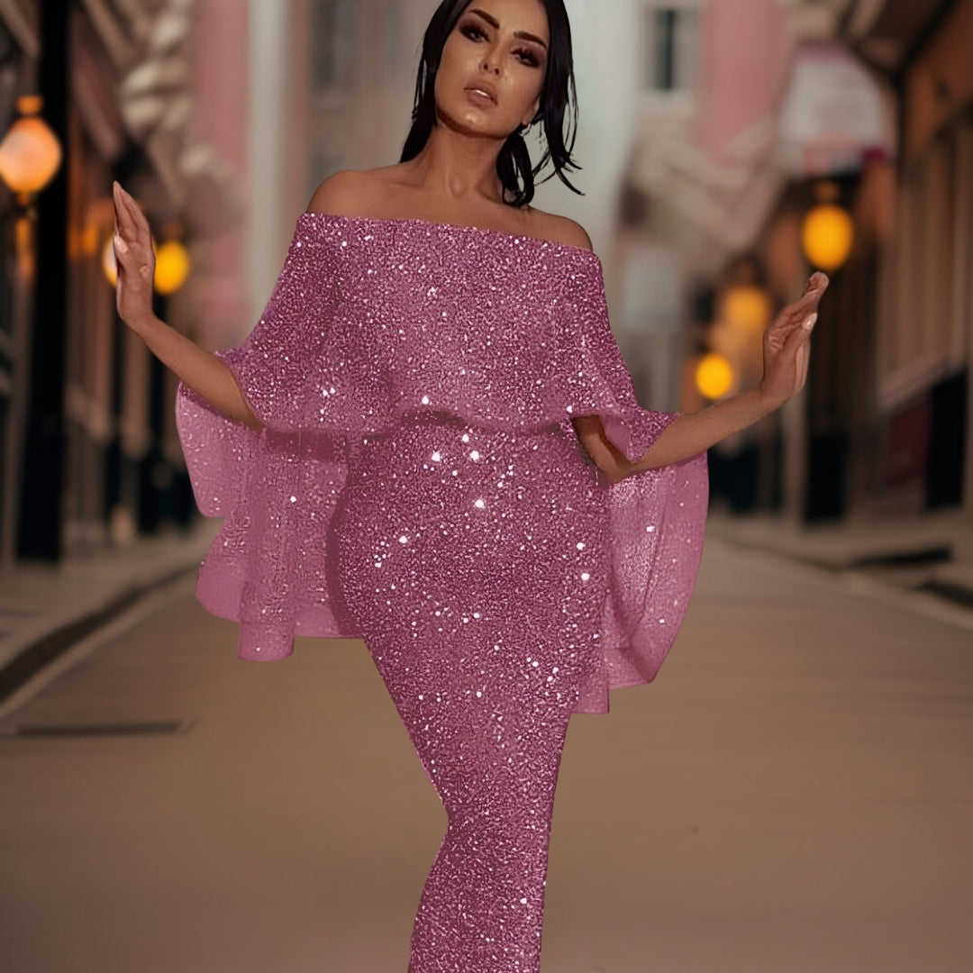 Robe rose pailletée élégante portée par une femme dans une rue urbaine, éclairée par des lampadaires. Mode glamour, soirée chic, style tendance.