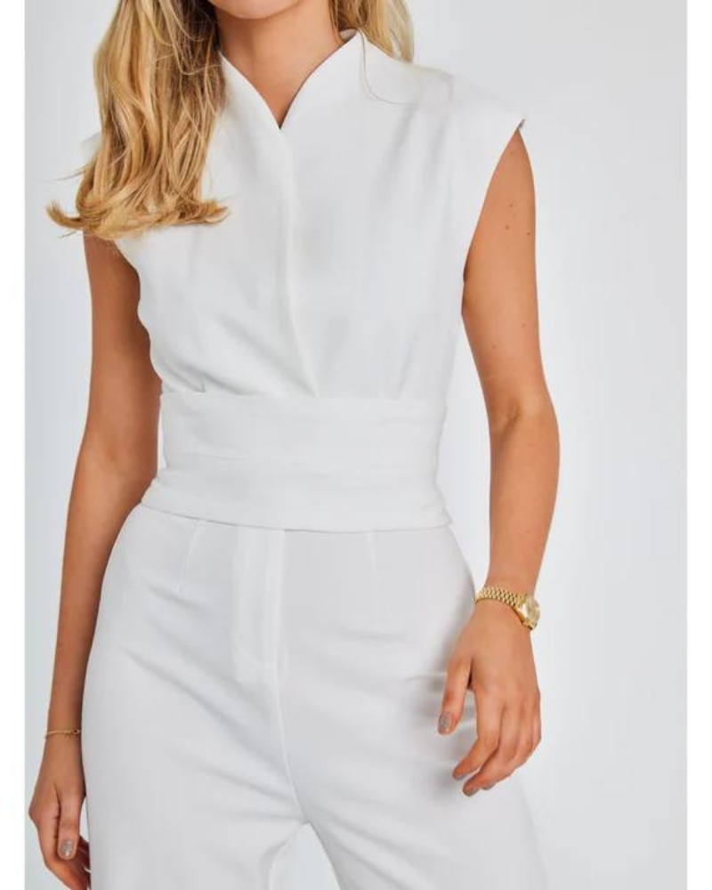 Femme en combinaison blanche élégante, sans manches, avec montre dorée. Mode féminine chic, tenue d'été sophistiquée, style minimaliste.