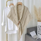 Châle en tricot beige avec boucle en cuir suspendu à côté d'une chemise blanche sur cintre, décoration intérieure moderne, style scandinave.