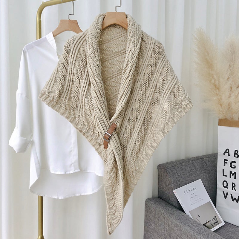 Châle en tricot beige avec boucle en cuir suspendu à côté d'une chemise blanche sur cintre, décoration intérieure moderne, style scandinave.
