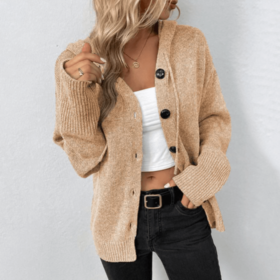 Femme portant un cardigan beige en tricot avec boutons noirs, débardeur blanc et jean noir. Mode automne, style décontracté, tenue élégante.