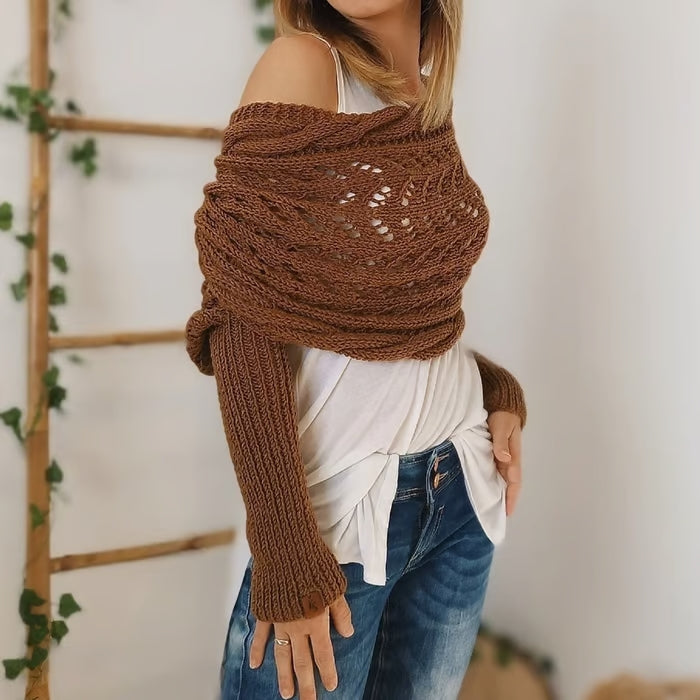 Femme portant un pull tricoté marron, style bohème, avec épaules dénudées, sur un haut blanc et un jean. Mode automne, tendance tricot.