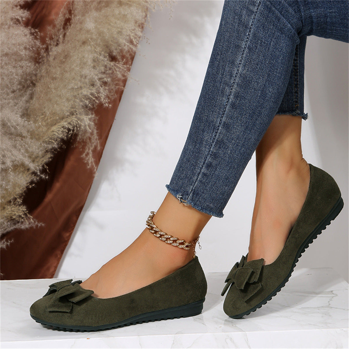 Chaussures ballerines vertes en daim avec nœud, portées avec un jean ajusté. Style décontracté et élégant pour femme. Accessoire mode tendance.