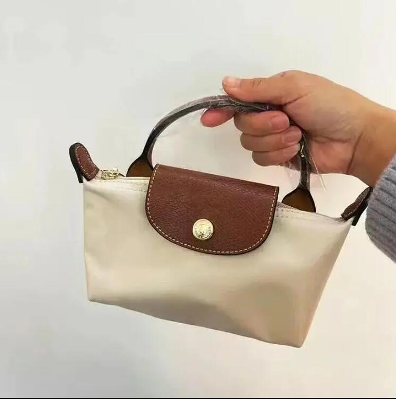 Sac à main beige et marron en cuir, porté par une main. Design élégant, compact, idéal pour la mode féminine. Accessoire tendance et pratique.