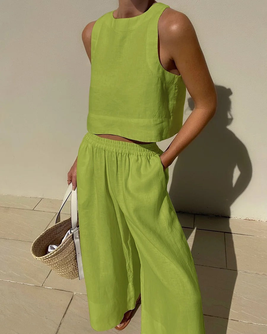 Femme en ensemble vert lime, top sans manches et pantalon ample, tenant un sac en osier. Mode estivale, tenue décontractée, style moderne.