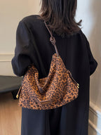Sac à main léopard en tissu, porté par une femme en manteau noir. Accessoire mode tendance, design élégant, idéal pour un look chic et moderne.