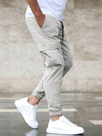 Pantalon cargo beige pour homme avec poches latérales, porté avec des baskets blanches et un t-shirt blanc. Mode décontractée masculine.