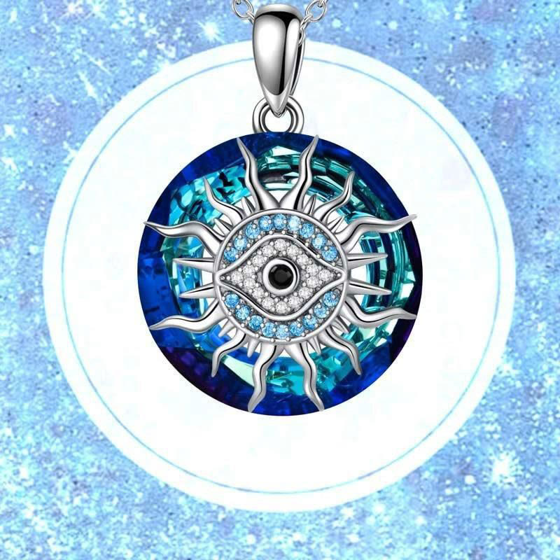Pendentif œil bleu argenté avec cristaux, motif soleil, sur fond bleu scintillant. Bijou protecteur, amulette tendance, style mystique.