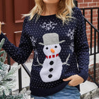 Femme portant un pull de Noël bleu marine avec motif bonhomme de neige, flocons de neige blancs, devant un décor urbain hivernal.