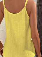 Débardeur jaune en tissu texturé, dos nu, bretelles fines, porté par une femme. Mode estivale, vêtement léger, style décontracté.