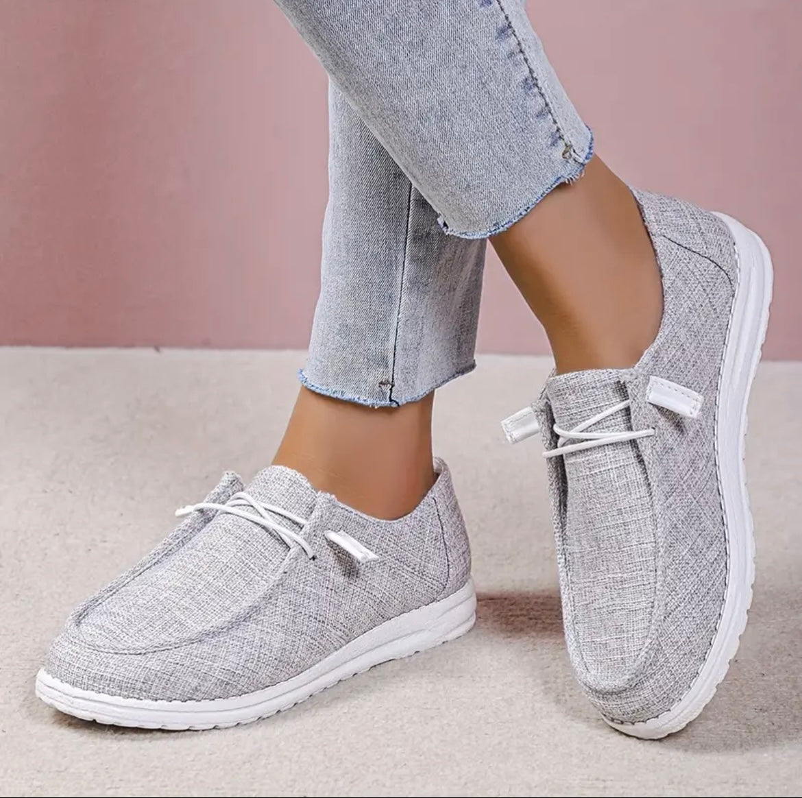 Chaussures décontractées en toile grise pour femmes, avec lacets blancs, portées avec un jean clair. Style moderne et confortable.