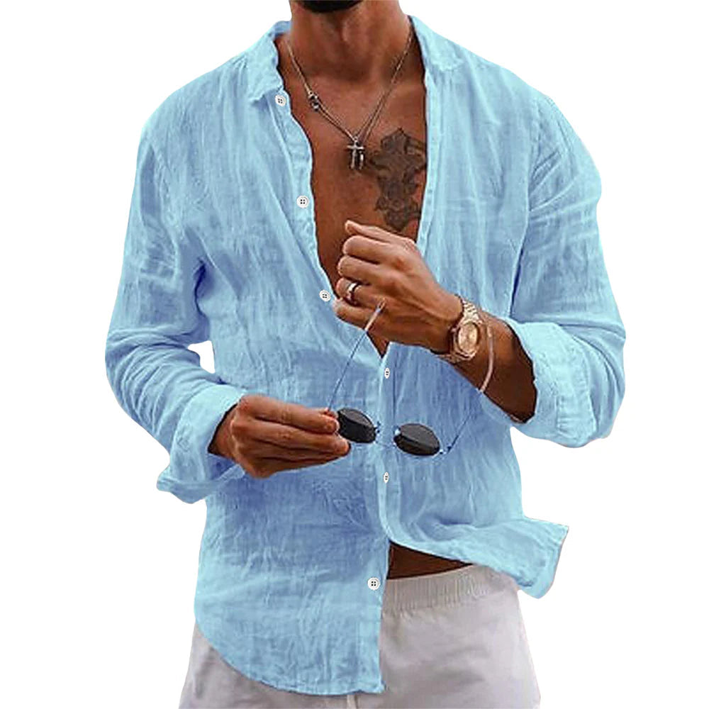Homme portant une chemise en lin bleu clair, manches retroussées, tenant des lunettes de soleil. Style décontracté, mode estivale masculine.