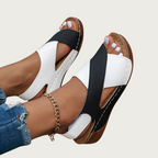 Sandales femme noires et blanches à talon plat, portées avec un jean et bracelet chaîne doré. Chaussures d'été élégantes et confortables.