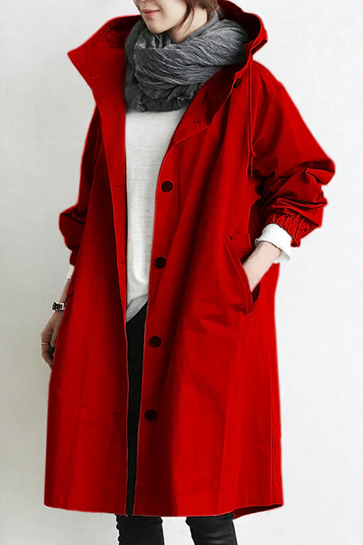 Femme portant un manteau rouge vif avec capuche, écharpe grise et chemise blanche. Mode automne, style décontracté, tendance vestimentaire.