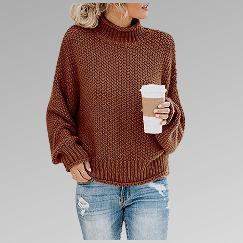 Femme portant un pull en maille marron avec un col roulé, tenant un gobelet de café, vêtue d'un jean déchiré. Mode automne-hiver, style décontracté.
