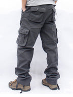 Pantalon cargo gris pour homme avec poches multiples, style décontracté, idéal pour randonnée. Chaussures de randonnée marron visibles.