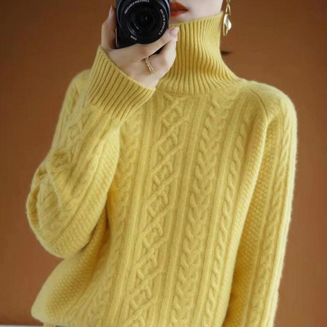 Femme portant un pull jaune à col roulé torsadé, tenant un appareil photo. Mode automne-hiver, style élégant et confortable.