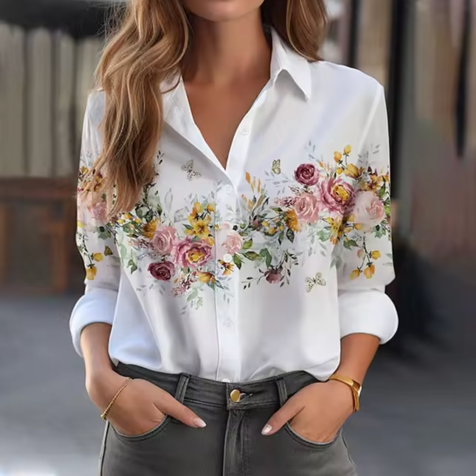 Chemise blanche à manches longues avec motif floral coloré, portée par une femme. Mode féminine élégante, tendance automne, style décontracté.