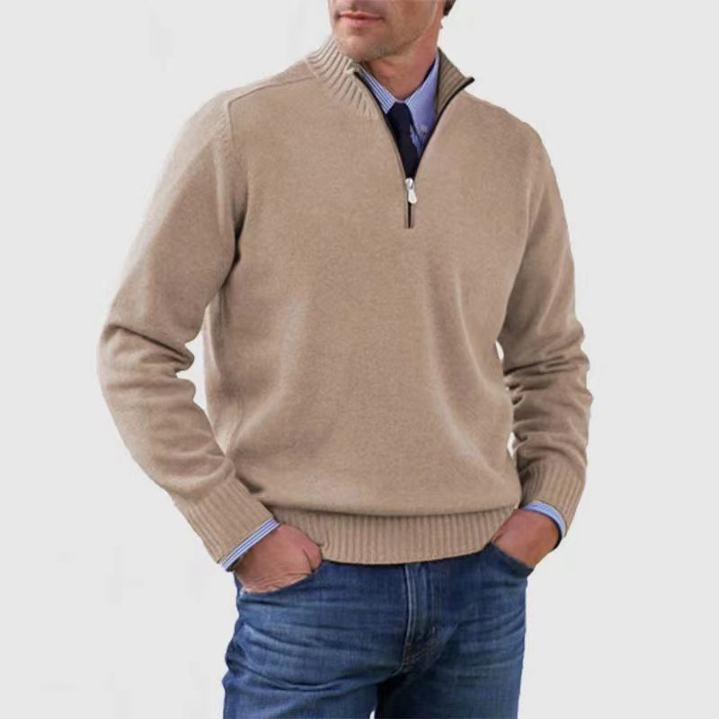 Homme portant un pull beige à col zippé, manches longues, sur une chemise bleue, associé à un jean bleu. Mode masculine élégante et décontractée.